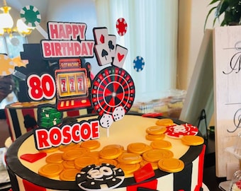 May include: A white and red casino themed cake with a black and white striped border. The cake is decorated with gold coins, playing cards, and a roulette wheel. The cake is topped with a sign that says "Happy Birthday" and a slot machine with the number 80 on it. The cake also has the name "Roscoe" on it.