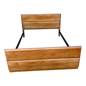 May include: A wooden bed frame with a headboard and footboard. The headboard and footboard are made of light brown wood with horizontal panels. Black metal supports connect the headboard and footboard.