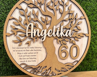 May include: A wooden, round, layered plaque featuring a tree design. The name "Angelika" is cut out above the tree, with the number "60" on the right. The plaque includes a stand and a message in German.