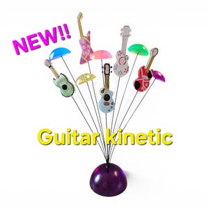 Könnte beinhalten: Eine kinetische Skulptur mit einer violetten kuppelförmigen Basis und mehreren dünnen Metalldrähten, die nach oben ragen, jeweils gekrönt von einer Miniaturgitarre und einem bunten, durchscheinenden Kunststoffschirm. Der Text NEW!! und Guitar kinetic ist sichtbar.