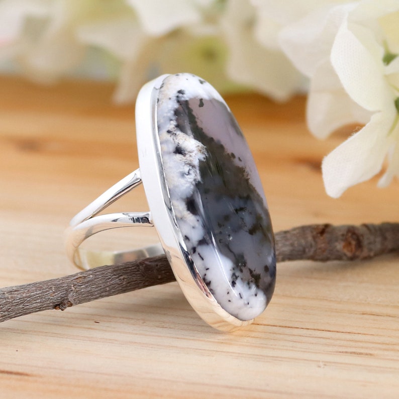 May include: A silver ring featuring a large oval-shaped black and white agate gemstone. The ring has a simple band with a split design.