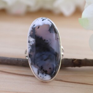 May include: A silver ring featuring a large oval-shaped black and white agate gemstone. The gemstone has a swirling pattern of black and white.