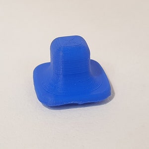May include: A small, blue, 3D printed square with a rounded top and a flat base.
