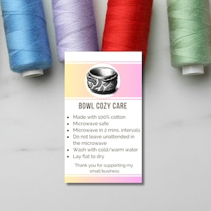 May include: A pink and yellow card with a black and white illustration of a bowl cozy. The card has the text "BOWL COZY CARE" and a list of care instructions: "Made with 100% cotton, Microwave safe, Microwave in 2 mins. intervals, Do not leave unattended in the microwave, Wash with cold/warm water, Lay flat to dry, Thank you for supporting my small business."