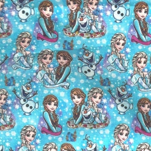 May include: A light blue fabric featuring a repeating pattern of characters from the animated film "Frozen." The design includes images of Elsa, Anna, and Olaf, along with snowflakes. The overall theme is a winter wonderland.