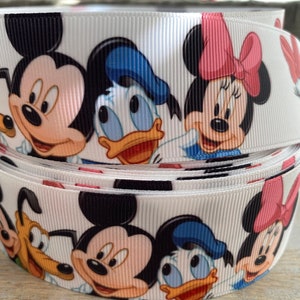 May include: White ribbon featuring a repeating pattern of Disney characters, including Mickey Mouse, Minnie Mouse, Donald Duck, and Pluto. The ribbon is rolled up, showcasing the colorful cartoon faces. This ribbon is suitable for crafts and gift wrapping.