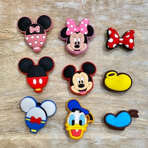 Puede incluir: Nueve amuletos de zapatos de personajes de dibujos animados coloridos con Mickey Mouse, Minnie Mouse, Donald Duck y Goofy. Los amuletos est&aacute;n hechos de goma y tienen una variedad de colores y dise&ntilde;os.