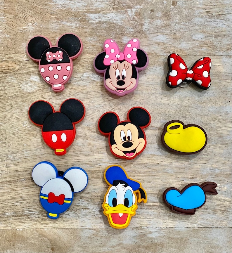 Puede incluir: Nueve amuletos de zapatos de personajes de dibujos animados coloridos con Mickey Mouse, Minnie Mouse, Donald Duck y Goofy. Los amuletos est&aacute;n hechos de goma y tienen una variedad de colores y dise&ntilde;os.