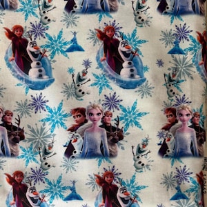 Pode incluir: Tecido branco com um padrão repetido de personagens e elementos do filme de animação "Frozen". O design inclui imagens de Elsa, Anna, Olaf, flocos de neve e outras imagens relacionadas em tons de azul, roxo e branco.