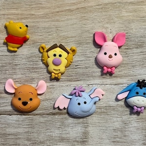 May include: Six colorful cartoon character figurines, including Winnie the Pooh, Piglet, Tigger, Eeyore, and two others. The figurines are made of a soft, pliable material and are perfect for crafts or decorations.