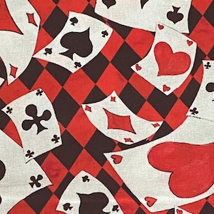 May include: A white fabric with a red and black diamond pattern. The fabric is covered with playing cards with different suits, including hearts, spades, diamonds, and clubs. The cards are in various positions and sizes.