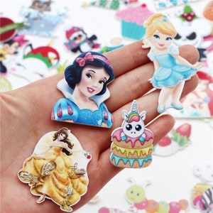 May include: A collection of colorful, cartoon character stickers featuring Snow White, Cinderella, Belle, and a unicorn on a cake. The stickers are in various shapes and sizes, with vibrant colors and detailed designs, perfect for crafts.