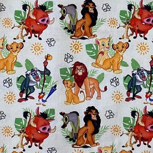 May include: A white fabric with a repeating pattern of cartoon characters from the Lion King movie. The characters include Simba, Nala, Pumbaa, Timon, and Scar. The fabric is decorated with green leaves, yellow suns, and brown paw prints.