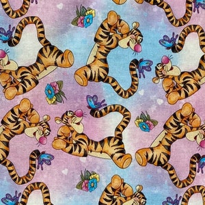 May include: A pink and blue fabric with a repeating pattern of cartoon orange and black tigers. The tigers are in various poses, including sitting, standing, and walking. There are also small blue butterflies and pink flowers scattered throughout the fabric.