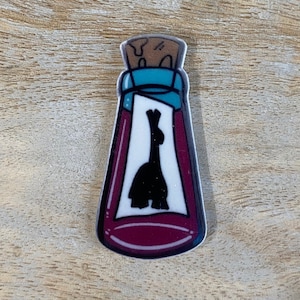 May include: A colorful, cartoon-style bottle-shaped sticker. The bottle is filled with a dark red liquid and has a white label with a black silhouette of a rabbit. The bottle has a teal neck and a cork stopper.