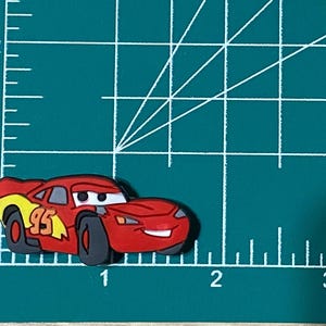 May include: Red and yellow cartoon race car with the number 95 on the side. The car has a smiling face and black wheels.