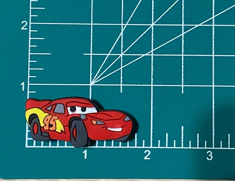 May include: Red and yellow cartoon race car with the number 95 on the side. The car has a smiling face and black wheels.