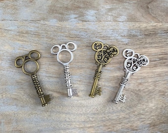May include: Four decorative keys with Mickey Mouse-shaped heads. The keys are in various metallic finishes: antique brass, silver, and bronze. Each key has a different design on the handle and key bit, adding unique detail to each piece.