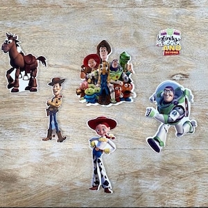 May include: A set of Toy Story character stickers featuring Woody, Buzz Lightyear, Jessie, and a group shot of the characters. The stickers are on a wooden background. The text "Infinity and Beyond" is included in the image.