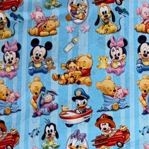 Könnte beinhalten: Ein hellblauer Stoff mit einem sich wiederholenden Muster von Disney-Figuren, darunter Micky und Minnie Maus, Winnie Puuh und Donald Duck. Die Figuren sind im Baby-Stil dargestellt, mit einem gestreiften Hintergrund.