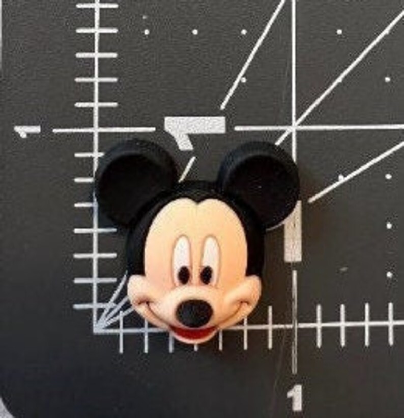 May include: A black and red cartoon character with large ears and a big smile. The character is Mickey Mouse.