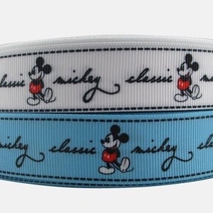 Op de afbeelding: Twee rollen witte en blauwe lint met een herhalend patroon van Mickey Mouse en de tekst "classic mickey".