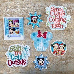 Puede incluir: Un conjunto de diez parches termoadhesivos con temática navideña que representan a los personajes de Mickey Mouse y Minnie Mouse. Los parches incluyen una escena de ventana con Mickey Mouse, Minnie Mouse, Donald Duck y Goofy, una escena de invierno con Mickey Mouse y Minnie Mouse, un diseño de Santa Claus está llegando a la ciudad, un diseño de bebé hace frío afuera y una escena de castillo con Mickey Mouse y Minnie Mouse.