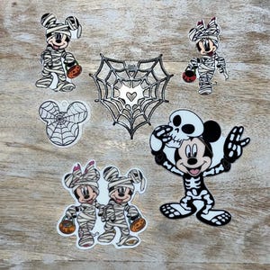 Può includere: Adesivi a tema Halloween con Topolino e Minnie Mouse in costume da mummia, uno scheletro di Topolino e un disegno a ragnatela. Gli adesivi sono nei colori nero, bianco, arancione e rosso.