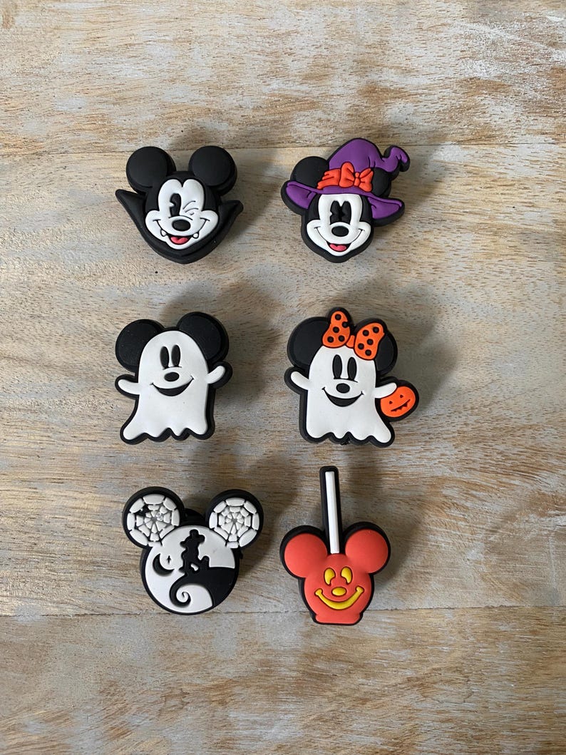 K&ouml;nnte beinhalten: Sechs Halloween-Schuhanh&auml;nger mit Mickey und Minnie Mouse. Designs umfassen einen Hexenhut, einen Geist und S&uuml;&szlig;igkeiten. Die Farbpalette umfasst Schwarz, Wei&szlig;, Orange und Lila. Ideal, um Schuhen eine festliche Note zu verleihen.