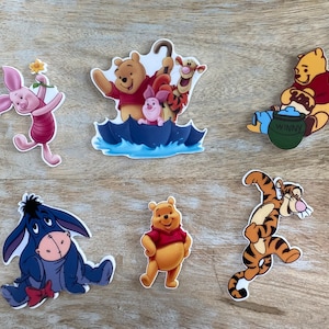May include: A set of seven Winnie the Pooh character stickers. The stickers feature Winnie the Pooh, Piglet, Tigger, Eeyore, and a honey pot. The stickers are all in different poses and have a cartoon style.