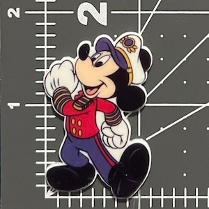 May include: A cartoon image of Mickey Mouse dressed as a captain. He is wearing a red jacket with gold buttons, blue pants with gold stripes, a white sailor hat with a gold band, and a blue and white striped shirt. He is smiling and has a white glove on his right hand.