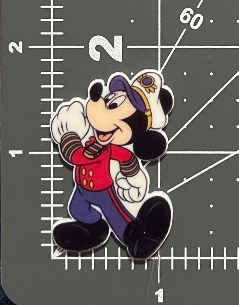 May include: A cartoon image of Mickey Mouse dressed as a captain. He is wearing a red jacket with gold buttons, blue pants with gold stripes, a white sailor hat with a gold band, and a blue and white striped shirt. He is smiling and has a white glove on his right hand.