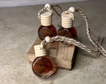 May include: Three brown glass bottles with wooden lids and a beige string attached to each. The bottles are sitting on a wooden surface.