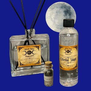 Könnte beinhalten: Zwei Glasflaschen mit Diffuseröl mit Etiketten, auf denen "Wiccan Spirit Handcrafted" und "Celestial Magic Full Moon Of" steht. Die Flaschen befinden sich vor einem blauen Hintergrund mit einem Vollmond dahinter.