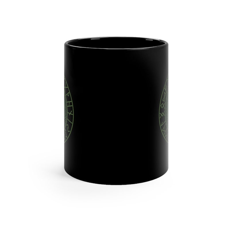 May include: Black ceramic coffee mug with a green circular design featuring a symbol and runes. The design is on both sides of the mug.