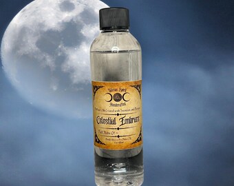 May include: A clear glass bottle with a black cap, labeled "Celestial Embrace" with a full moon graphic. The label also includes the text "Wiccan Spirit" and "Handcrafted". The bottle contains a clear liquid and is 4 fl oz.