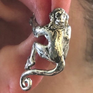 May include: Silver monkey ear cuff. The monkey is climbing with its tail curled around the ear.
