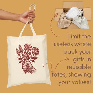 May include: Cream tote bag featuring a red illustration of a hand holding roses and wheat. The bag is held by a hand. Text on the image reads: "Limit the useless waste - pack your gifts in reusable totes, showing your values!"