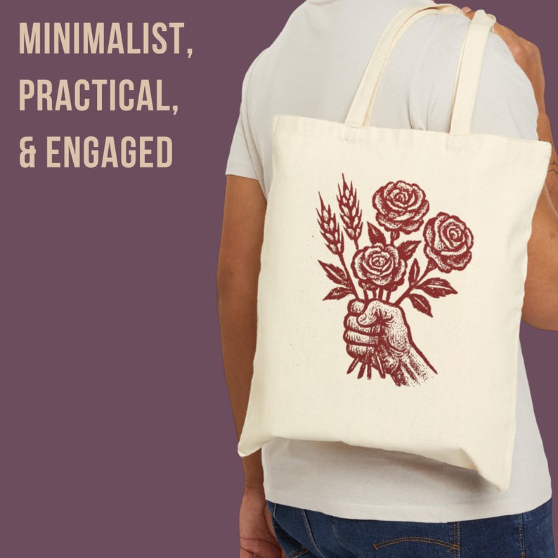 May include: A cream tote bag featuring a red illustration of a hand holding roses and wheat. The bag has the words "MINIMALIST, PRACTICAL, & ENGAGED" printed on the left side. The bag has two cream-colored handles.