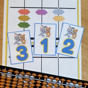 Puede incluir: Un ábaco educativo colorido con una hoja de trabajo impresa con los personajes de dibujos animados Tom y Jerry y los números 1, 2 y 3. El ábaco tiene cuentas de madera y un marco negro, ideal para aprender.
