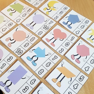 Op de afbeelding: Een set van 10 printbare kaarten met verschillende vormen met benen en nummers. Elke kaart heeft een vorm, zoals een hart, een ster, een pijl of een zeshoek, met benen en een nummerlijn met de nummers 0-10.