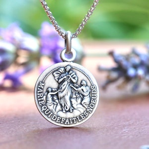 Può includere: Collana d'argento con un ciondolo rotondo che raffigura Maria, Sciogli-Nodi, con l'iscrizione "Marie qui défait les nœuds".