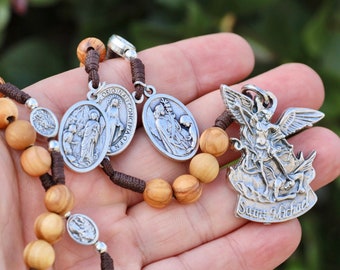 Może przedstawiać: Różaniec z brązowego drewna z srebrnymi koralikami i medalionami. Medaliony przedstawiają obrazy Matki Boskiej, św. Michała i innych postaci religijnych. Różaniec jest nawleczony na brązowy sznurek.