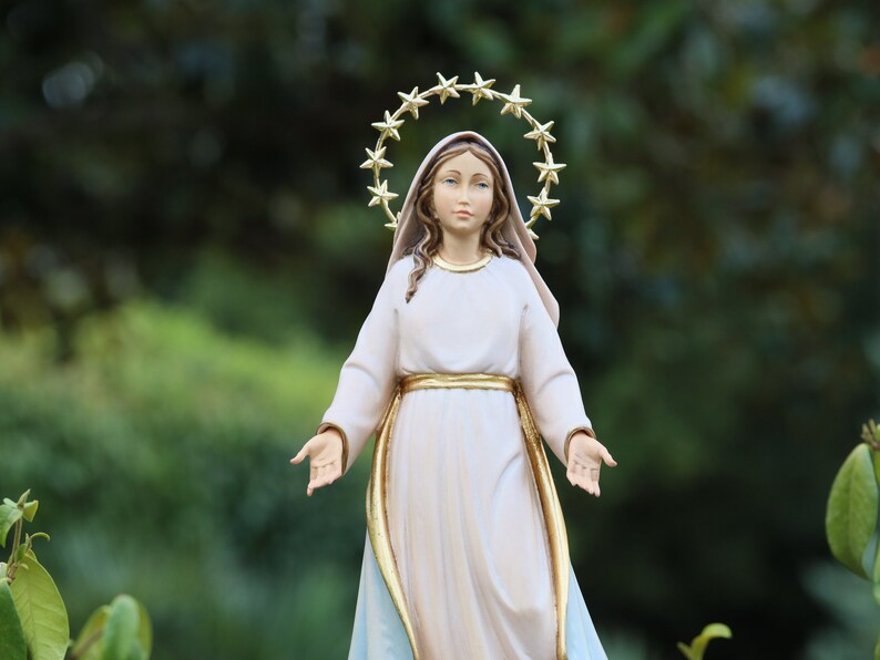 K&ouml;nnte beinhalten: Eine wei&szlig;e Statue der Jungfrau Maria mit einer goldenen Sternenkrone. Die Statue steht mit ausgestreckten Armen und tr&auml;gt ein wei&szlig;es Gewand mit einem goldenen G&uuml;rtel.