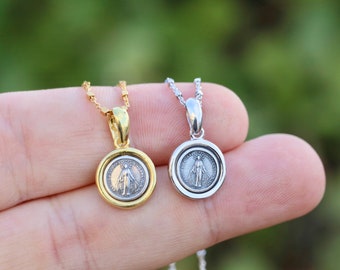 May include: Two silver necklaces with a round pendant featuring a depiction of the Virgin Mary. One necklace has a gold chain and the other has a silver chain.