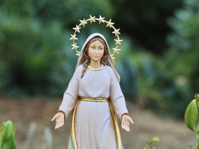 K&ouml;nnte beinhalten: Eine wei&szlig;e Statue der Jungfrau Maria mit einer goldenen Sternenkrone. Die Statue steht mit ausgestreckten Armen.