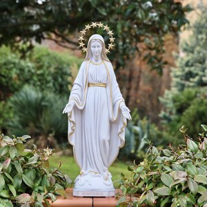 May include: White statue of the Virgin Mary with a gold star halo. The statue is standing on a base with the word "MEDJUGORJE" written on it.