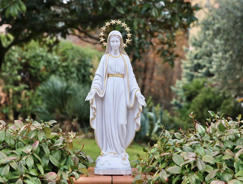 May include: White statue of the Virgin Mary with a gold star halo. The statue is standing on a base with the word "MEDJUGORJE" written on it.