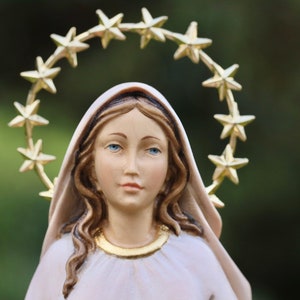 K&ouml;nnte beinhalten: Eine wei&szlig;e Figur einer Frau mit langen braunen Haaren, die einen wei&szlig;en Schleier und eine goldene Sternenkrone tr&auml;gt. Die Figur ist eine religi&ouml;se Figur.