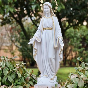 May include: White statue of the Virgin Mary with a gold star halo. The statue is standing on a base with the word "Medjugorje" inscribed on it.